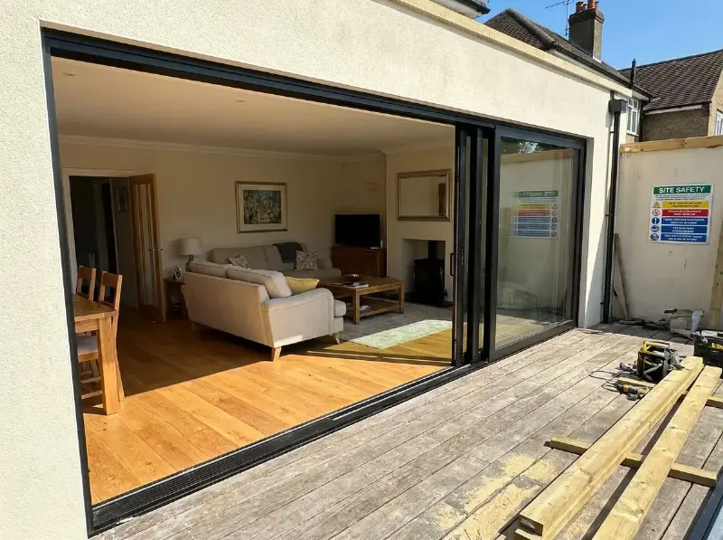 Open hefschuifraam in zwart aluminium tussen woonkamer en terras, drempel gelijk met de vloer