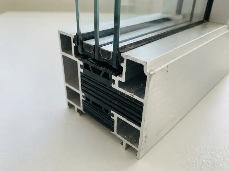 Doorsnede van een aluminium raamprofiel met de zwarte polyamide strook van de thermische onderbreking en driedubbel glas
